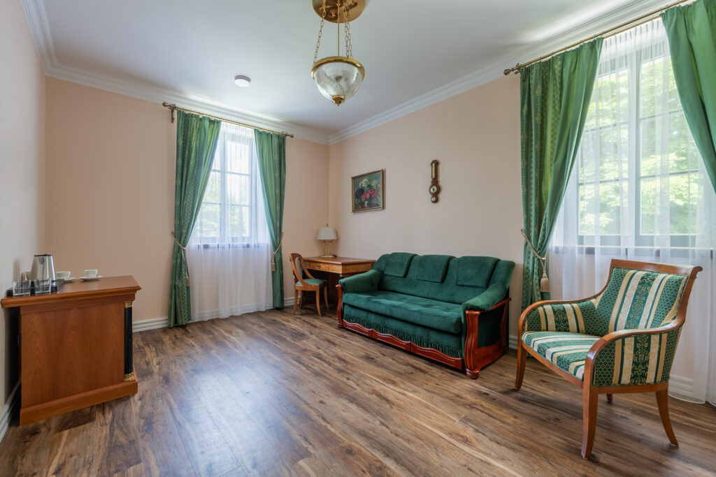 Pod Krásnou horou - pokoj Nefrit - záběr rozkládacího zeleného gauče, šatní skříně, velkého zrcadla a rustikální židle a židle s psacím stolem